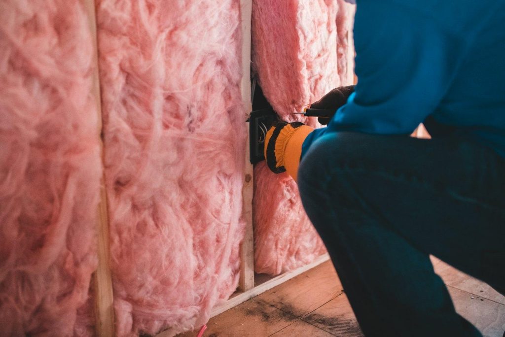 Crew member installing insulation between wall studs